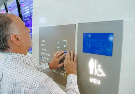 Man uses a tactile map to understand a restroom layout.