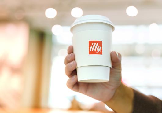 hand holding a cup of to-go coffee with illy logo 