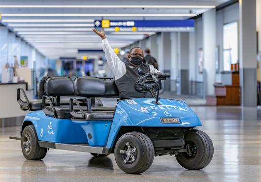 A cart driver shows off his blue Delta cart with enthusiasm