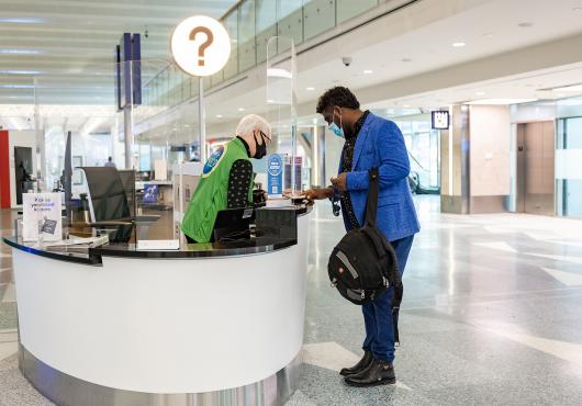 A man stands next to an information booth speaking to a volunteer