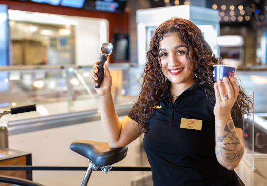 A smiling worker showing off freshly scooped icecream