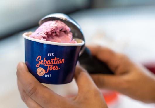 Strawberry ice cream being scooped into a cup