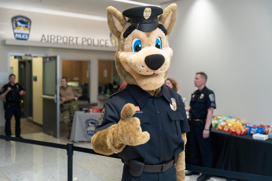 Officer Blue, Airport Police Department mascot, posing in front of APD offices