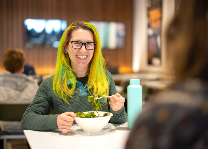 Person enjoying a salad from Crisp & Green.