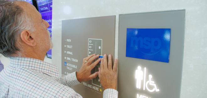Man using a tactile map to understand a restroom layout.