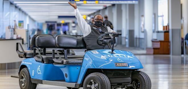 A cart driver shows off his blue Delta cart with enthusiasm