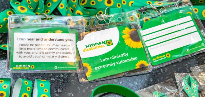 A closer look at a sunflower lanyard with a badge that reads "I am clinically extremely vulnerable" 