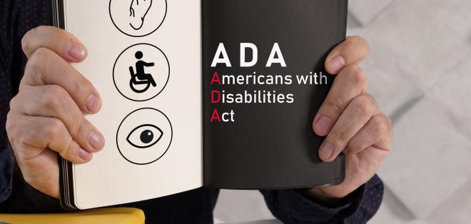 A person holds a book open to a page that reads "ADA"